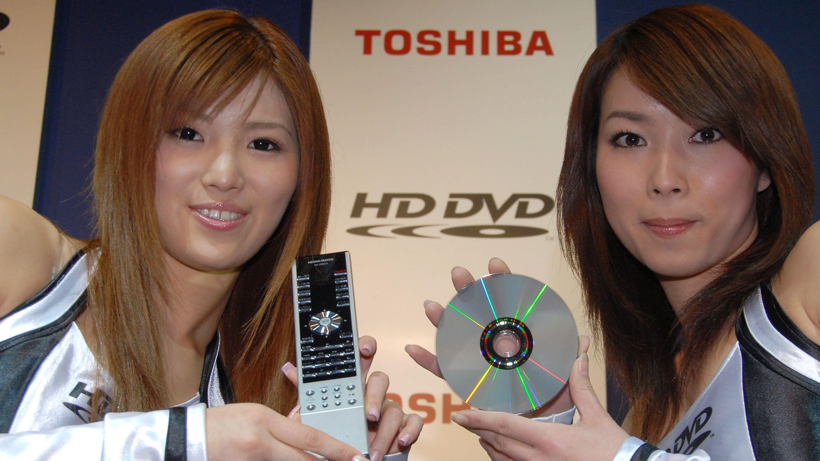 Two women hold up a DVD and remote to promote an HD DVD.