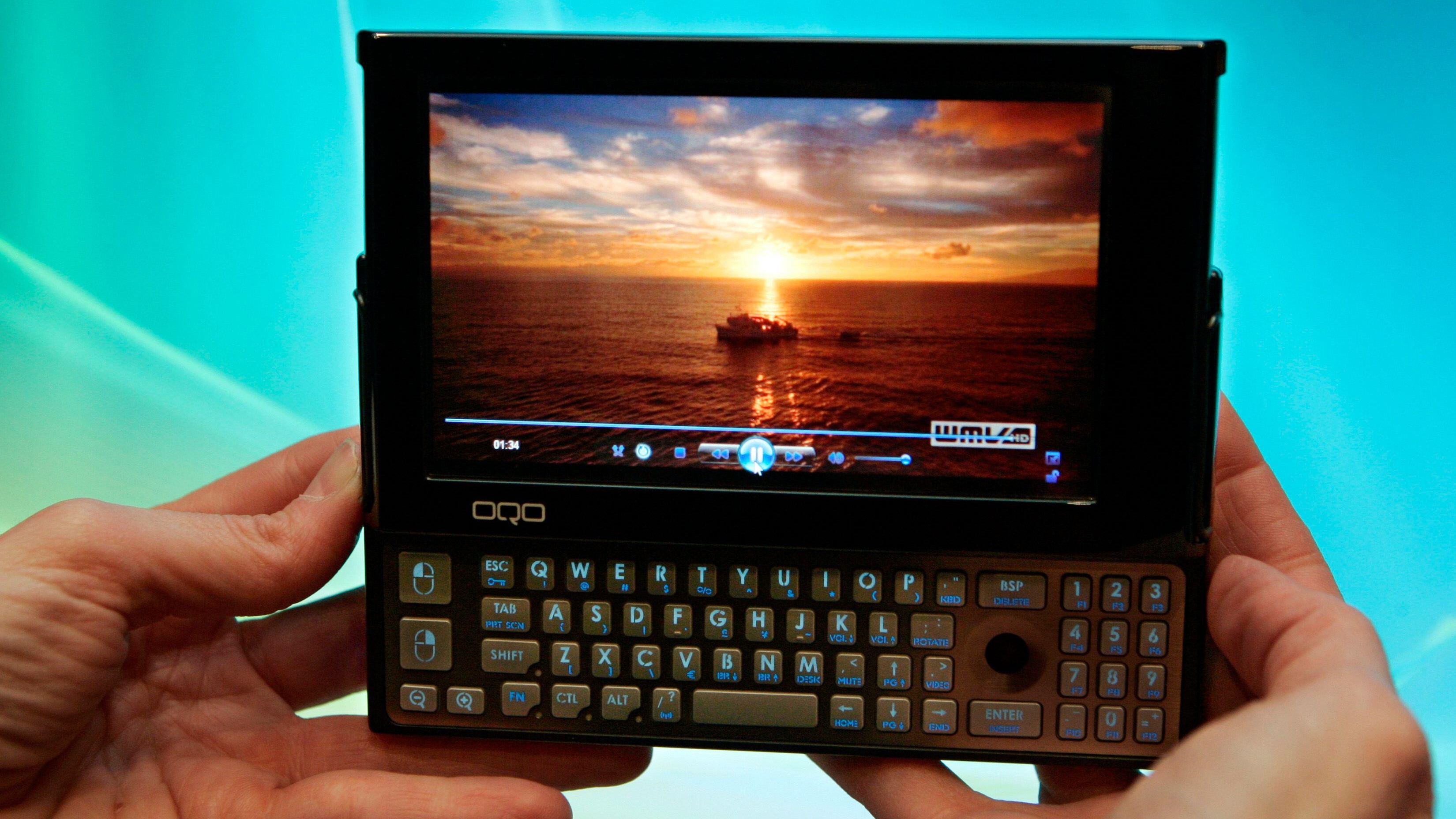 Fingers holding up a handheld PC with a slide out keyboard.