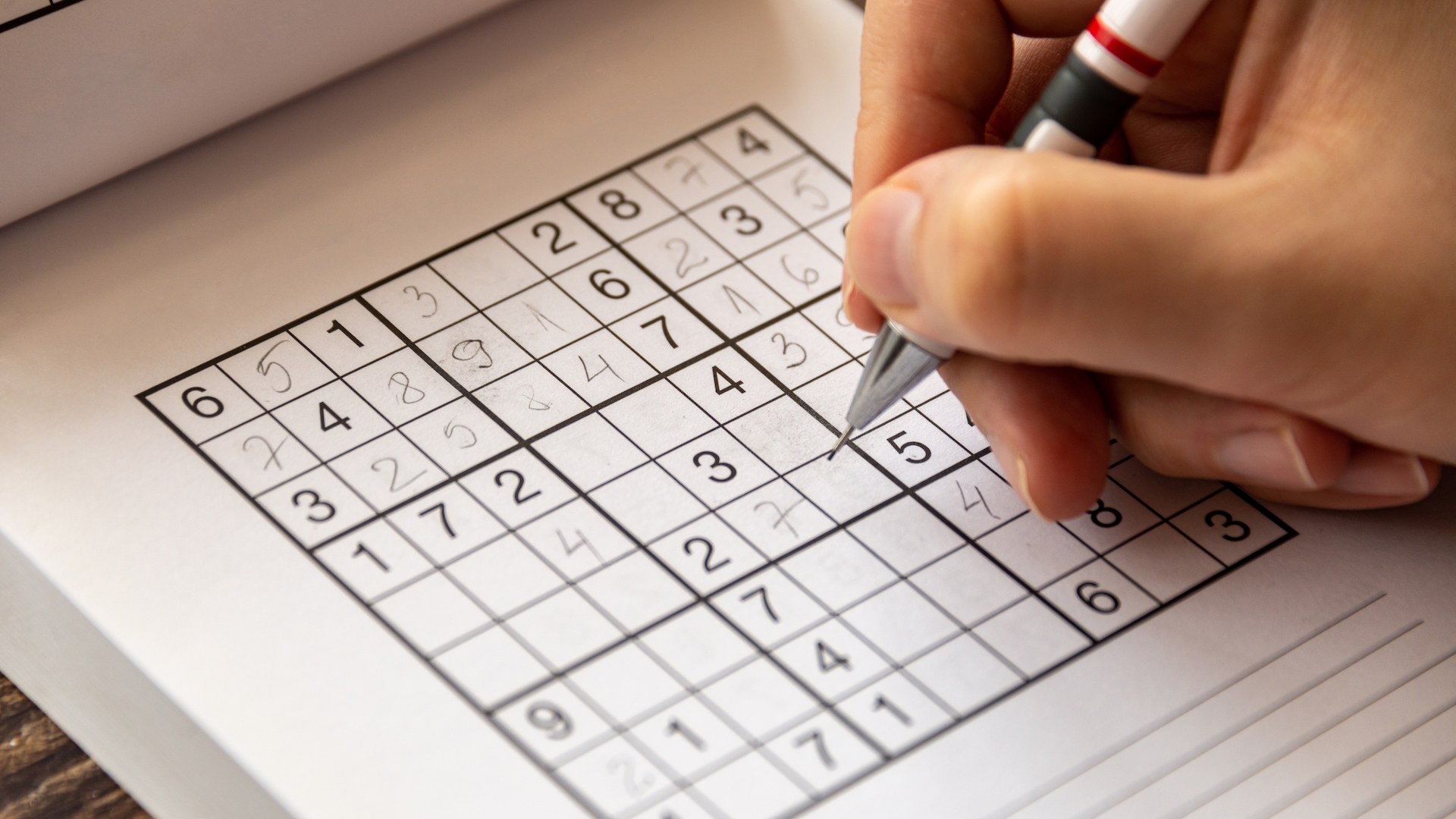 Photo of a person's hand as they fill out a sudoku puzzle