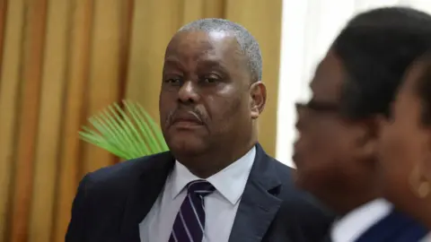 Reuters Garry Conille, wearing a suit and tie, attends a ceremony with members of the transition council