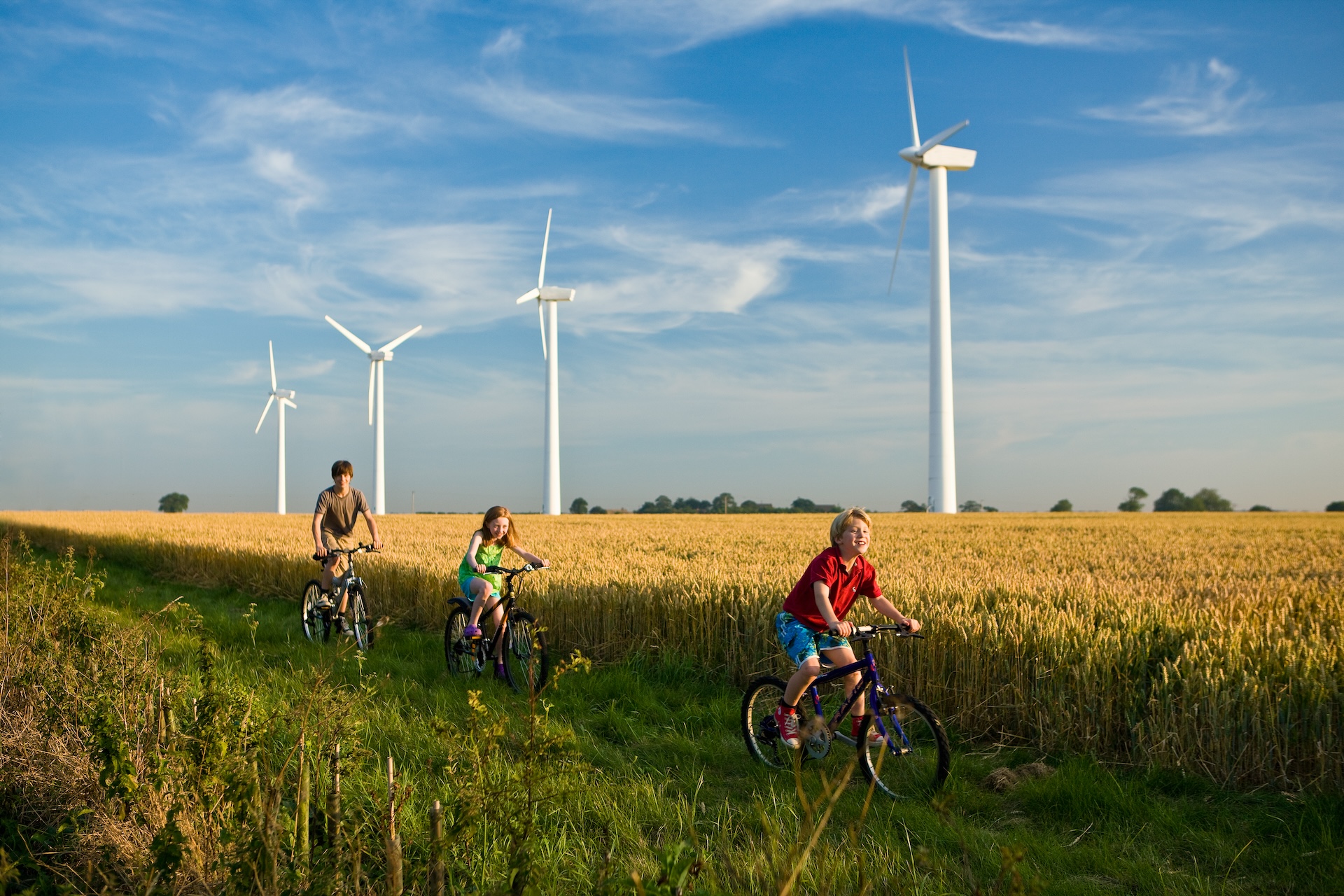 Children cycling past wind turbines