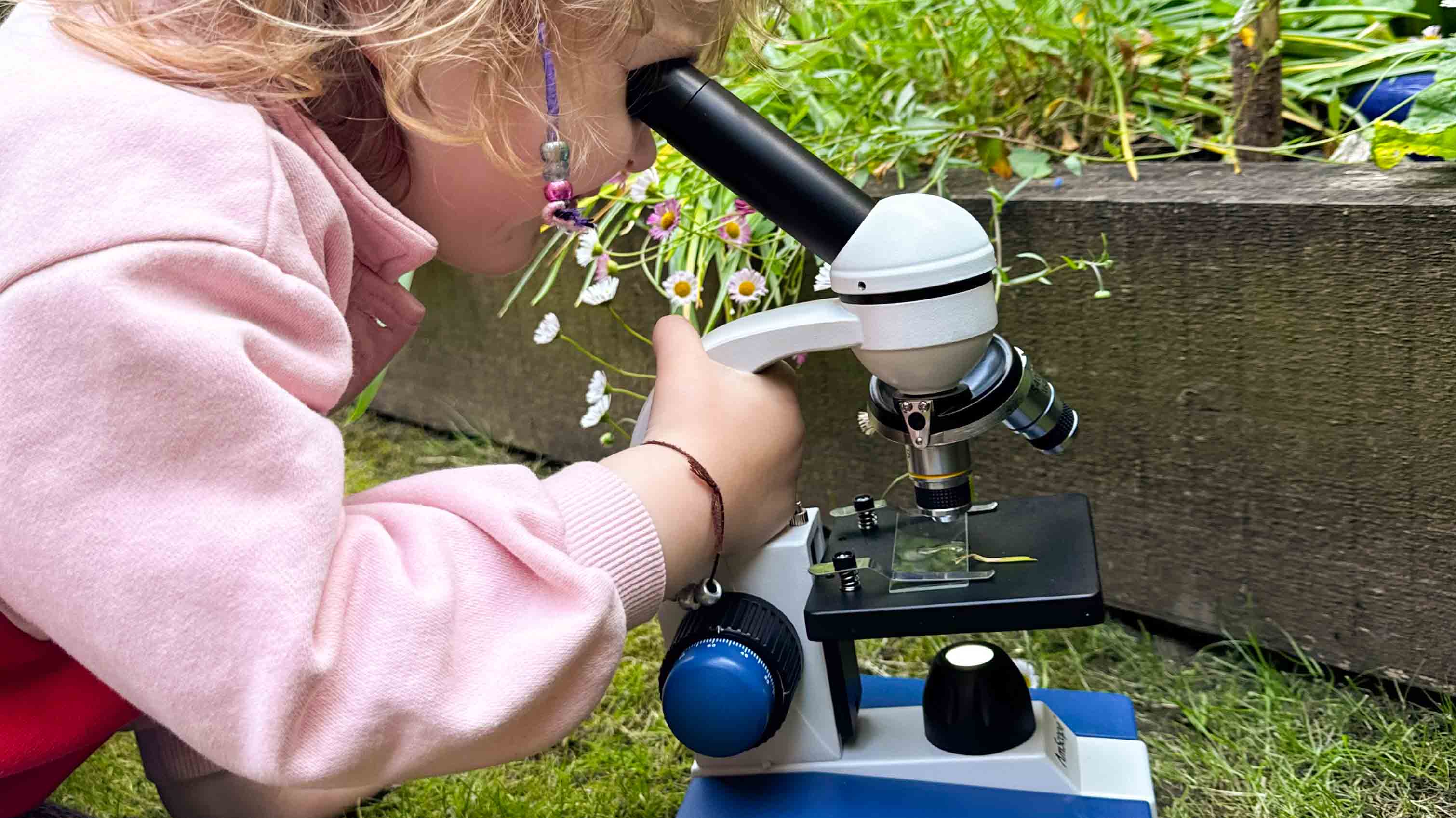 Microscope being used by a small child next to a pond outside