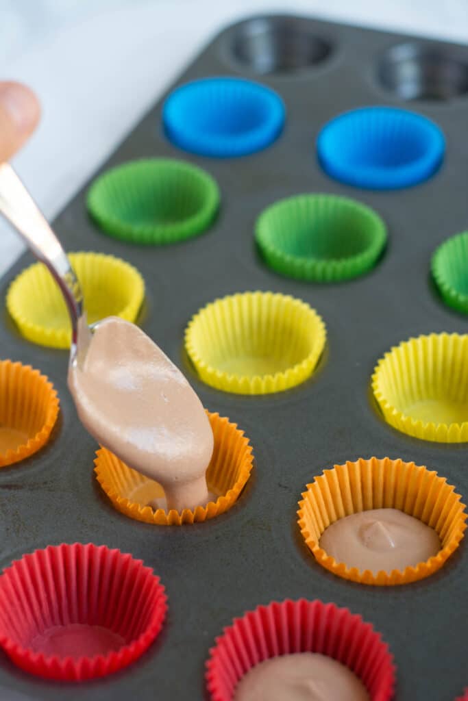 A photo of pouring the mixture from a spoon into a mini muffin pan.