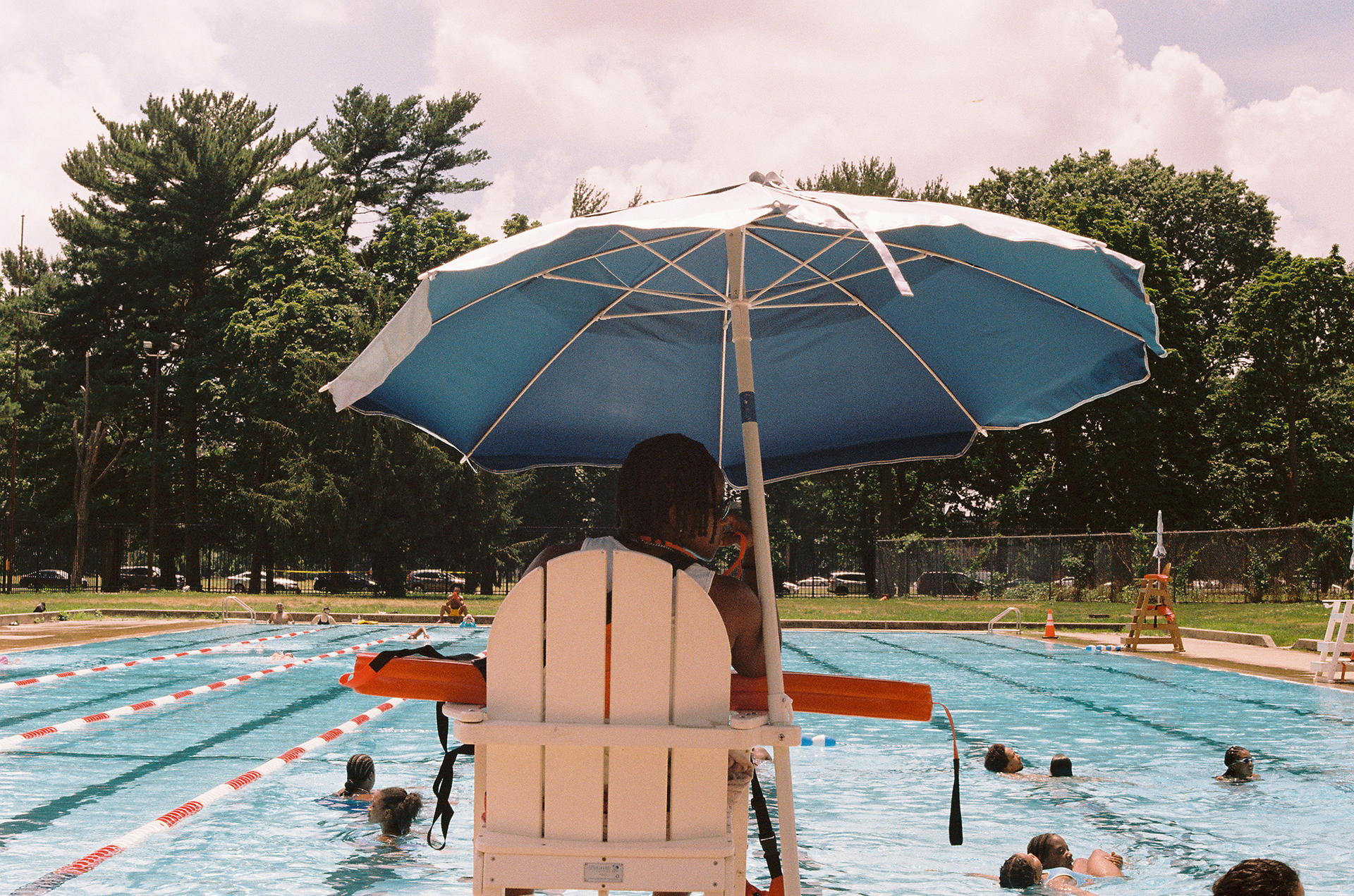 A lifeguard is watching over a public pool full of people.