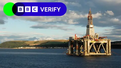 Getty Images Offshore rig in the sea near a coastal village at dusk