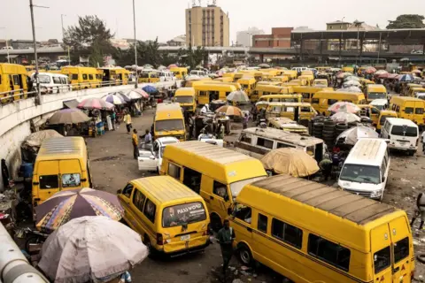 Getty Images Bus drivers wait for customers at the Obalende Bridge in Lagos, Nigeria