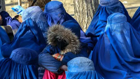 Rex/Shutterstock Afghan women wait to receive aid packages in Kabul