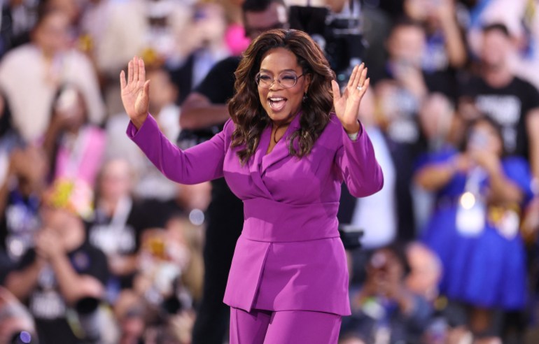 Oprah Winfrey walking onto the stage. She has her hands up.