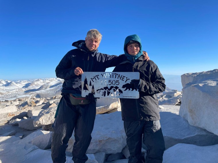 Thijs Koekkoek and his son hold a sign that reads, "Mt Whitney 14,505"