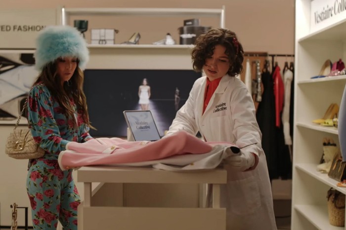 A woman offers a dress to another woman at a store