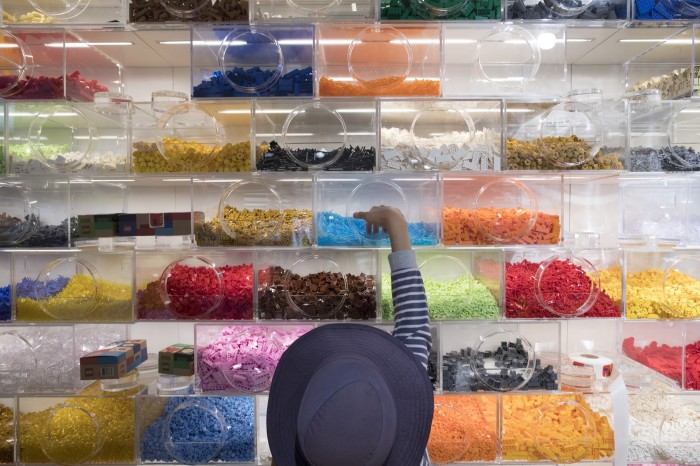 A child reaches up for Lego bricks on a shelf