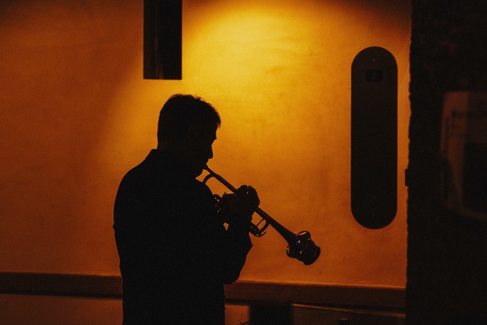 Silhouette of a trumpet player playing backstage in muted light 