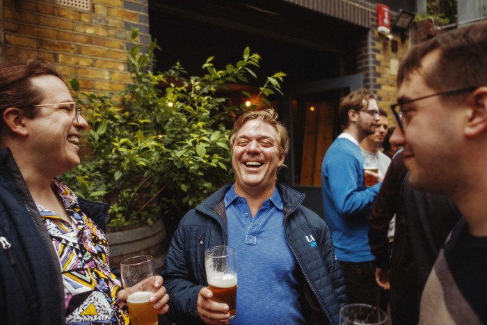 Three men drinking pints of beer outside a London pub