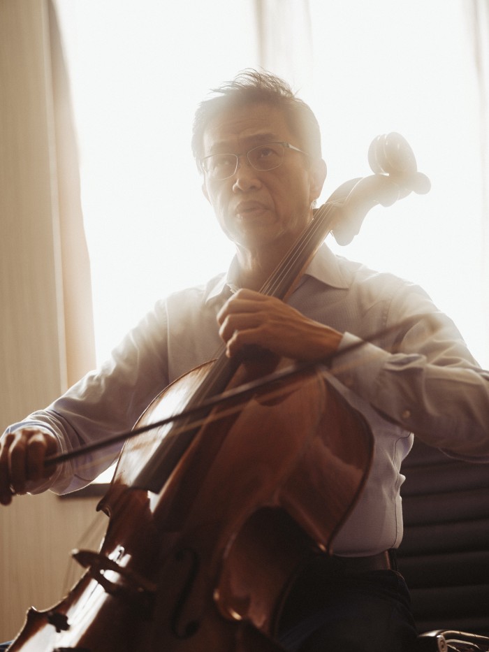 Portrait of a man playing a cello against a hotel window