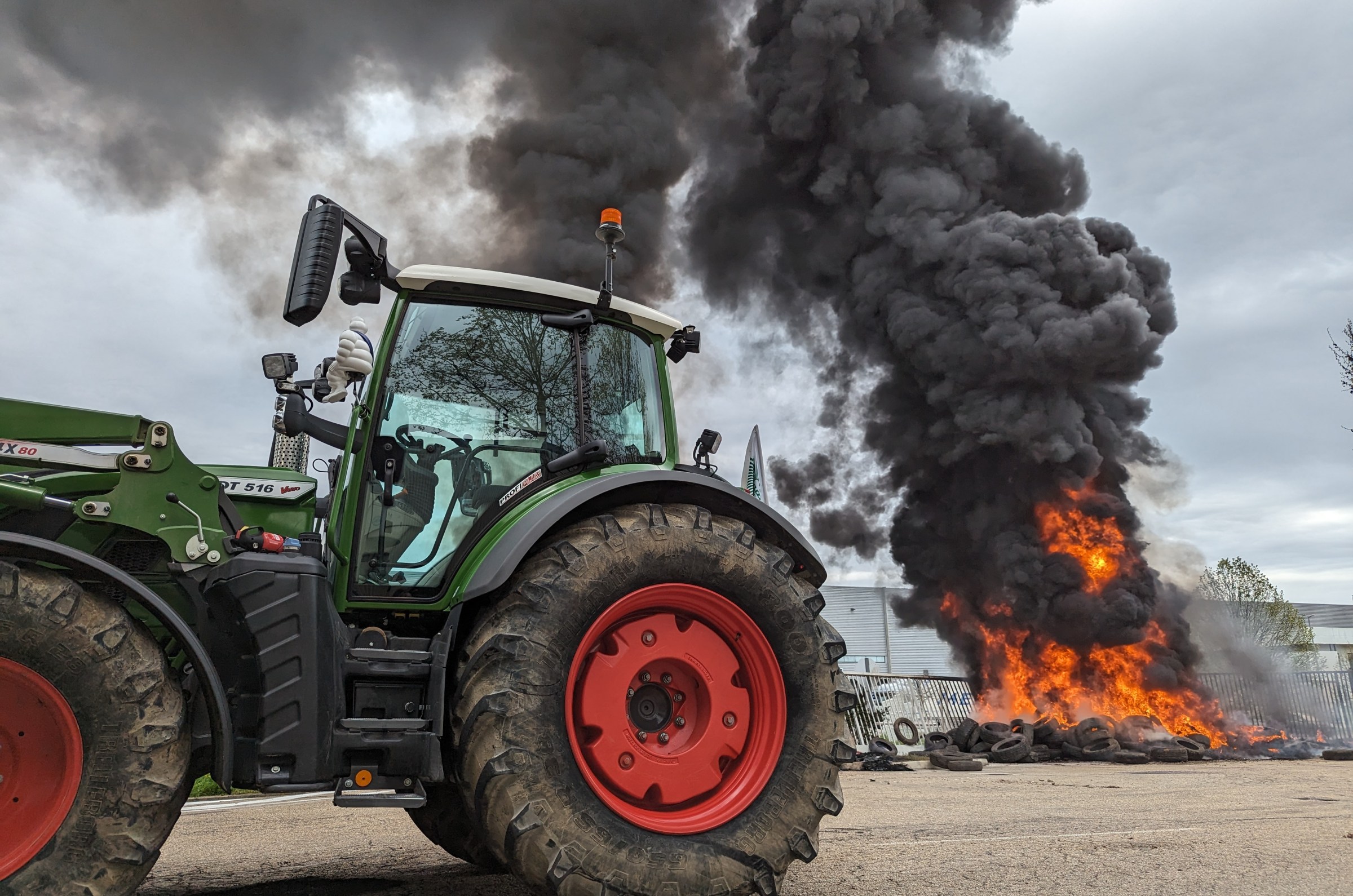 A tractor sitting in front of a tire fire.