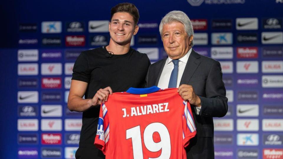 Julian Alvarez holds up a shirt at his unveiling for Atletico Madrid