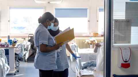 Nurses look at patient charts in a hospital ward