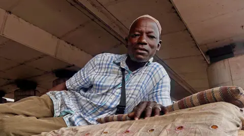 BBC  Liya’u Sa’adu lying on his mattress under a bridge in Lagos, Nigeria