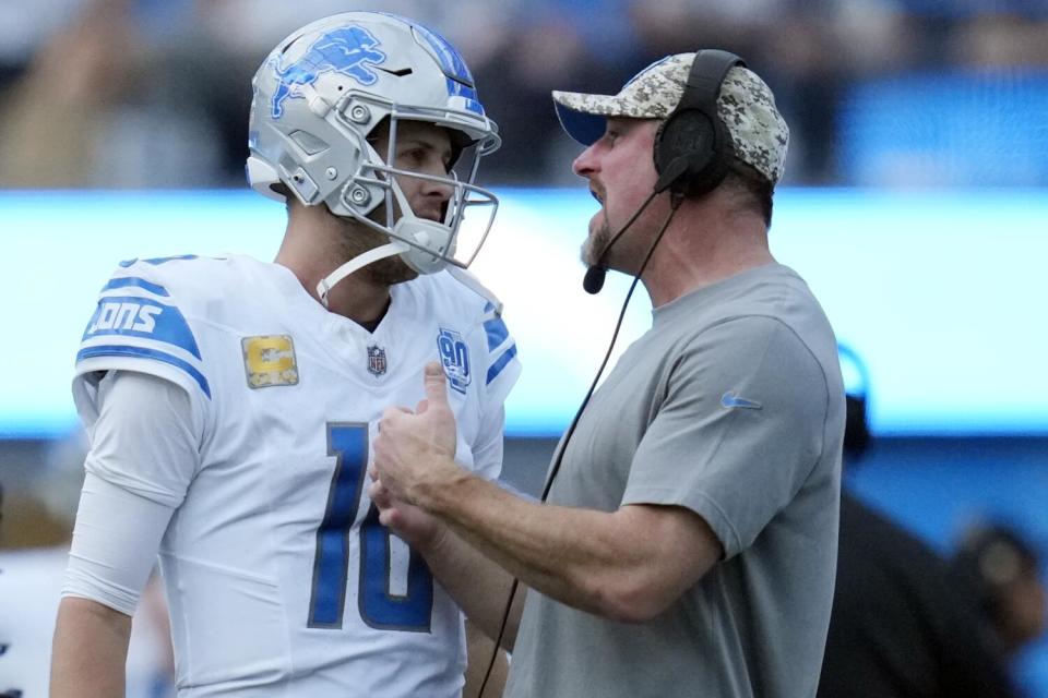 Lions coach Dan Campbell (right) talks to quarterback Jared Goff on the sideline.