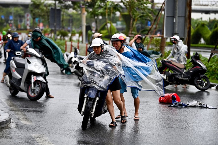 Motorcyclists struggle from the strong wind.