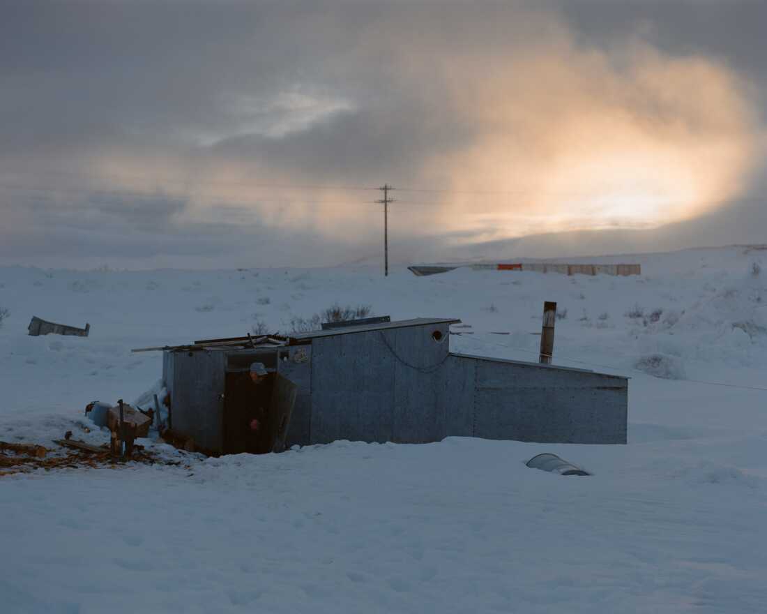 CANHR lead investigator and Qungasvik community organizer Simeon John goes to collect water outside his Maqi (steam house) near his home in Toksook Bay, Alaska. Historically, he says that the steam bath has played an important role in mental wellness within the community by providing neighbors with spaces to gather and share their concerns.