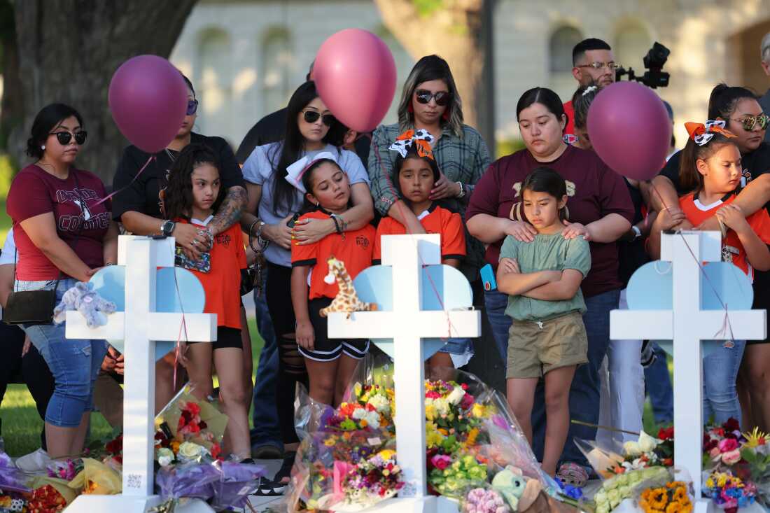 People visit memorials for victims of a mass shooting at Robb Elementary School in Uvalde, Texas. Nineteen children and two adults were killed after a man entered the school through an unlocked door and barricaded himself in a classroom where the victims were located. Law enforcement officers waited in the hallway for over an hour before entering the classroom and confronting the gunman.