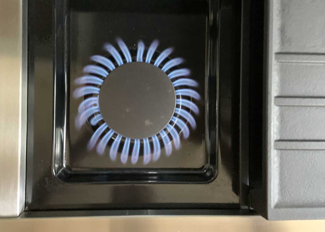 This photo shows the burner of a gas stove, with a ring of blue flames encircling the burner.