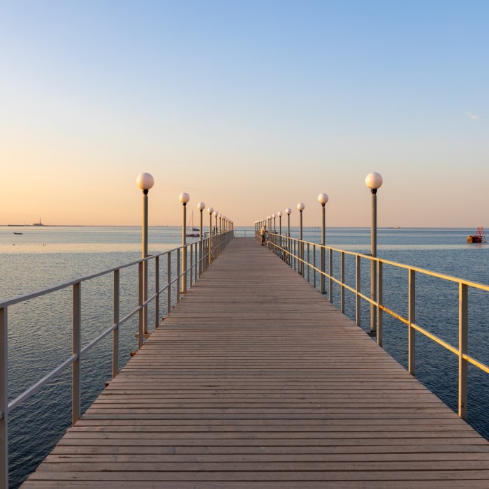 A wooden jetty jutting out into the sea under a sunset