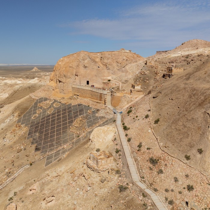 A rough track and steps leading to a structure that emerges from the mountainside 