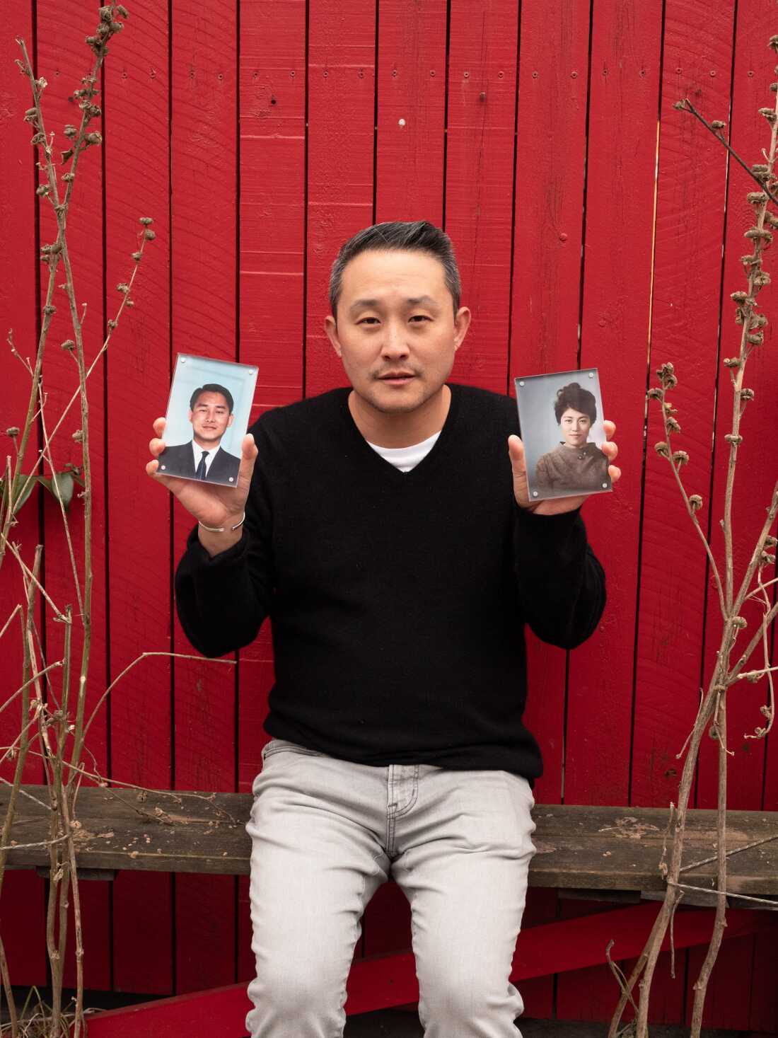 Tom Pyun, 46, a Korean American writer, poses for a portrait holding photos of his parents.