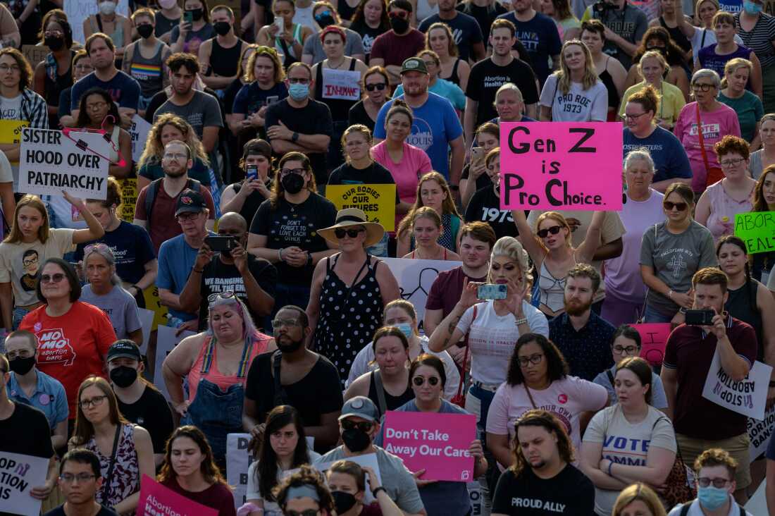 Abortion-rights activists demonstrate outside the Planned Parenthood in St. Louis on June 24, 2022, just after the Supreme Court struck down Roe v. Wade. The photo, shot from above, shows about 180 people gathered tightly together in a crowd, some carrying signs. One bright pink one reads: 