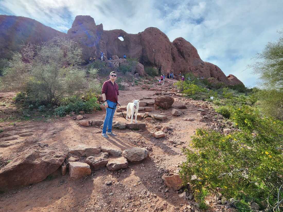 Ravi Coutinho and his dog, Finn, in March 2023. They are standing in a beautiful southwestern landscape -- red rock outcroppings against a blue sky. 