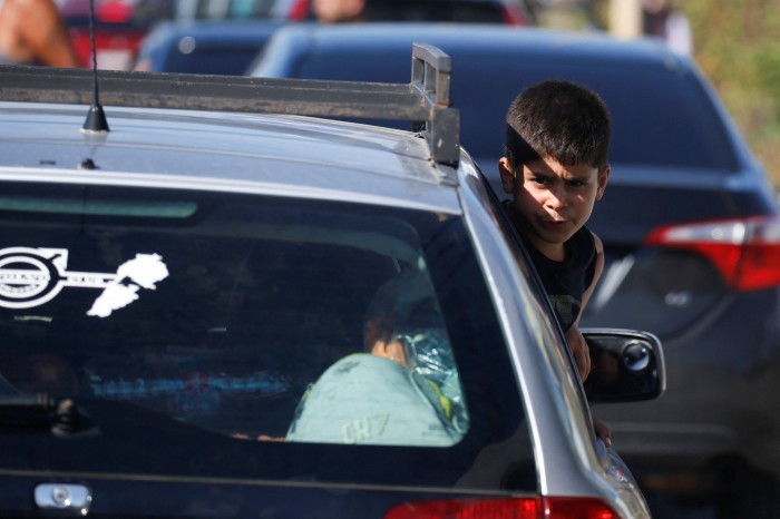 A boy looks out from a car window while people in heavy traffic drive north from Lebanon’s southern coastal city Sidon