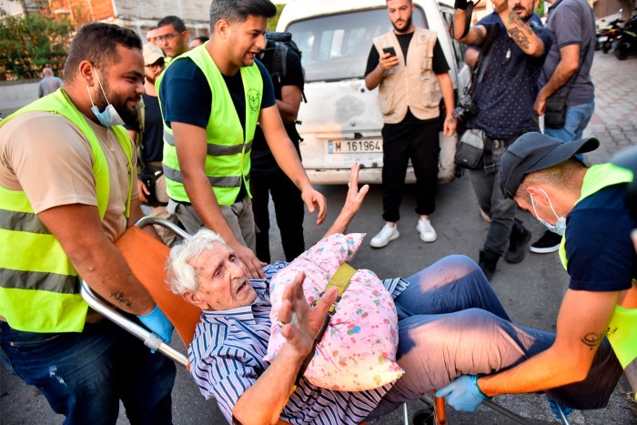 Volunteers carry an elderly man on a chair as people who fled their villages in southern Lebanon are received at an art institute transformed to a shelter for the displaced in Beirut