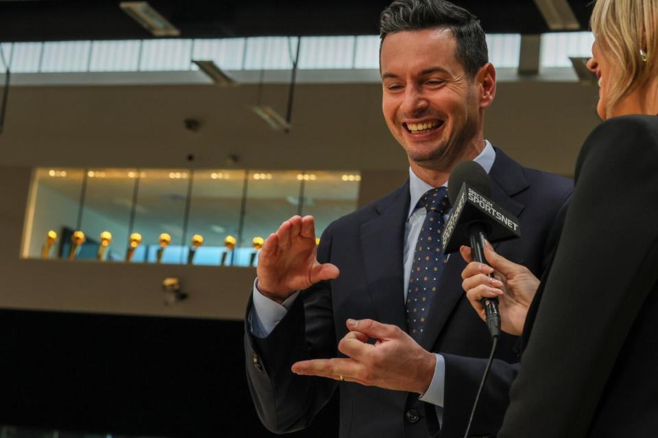 JJ Redick gestures while speaking to a broadcaster holding a microphone