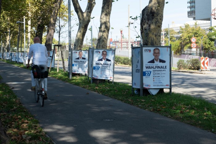 A cyclist passes Freedom party election posters in Vienna