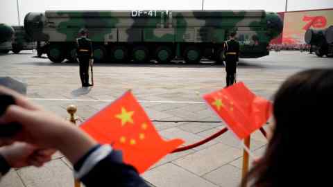 Spectators wave Chinese flags and watch military vehicles carrying DF-41 nuclear ballistic missiles during a parade to commemorate the 70th anniversary of the founding of China in Beijing in 2019