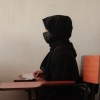 A teenage girl wearing a face mask, head scarf and long black robe listens to a math teacher at a tutoring center in Kabul. The center was established by a women's rights activist to circumvent a Taliban ban on girls attending secondary school. The activist said she has informal permission by Taliban authorities to run the center as long as teenage girls abide by a strict dress code.