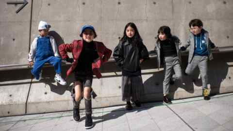 Five young attendees of Seoul Fashion Week dressed in designer clothing pose for photographers in October 2017