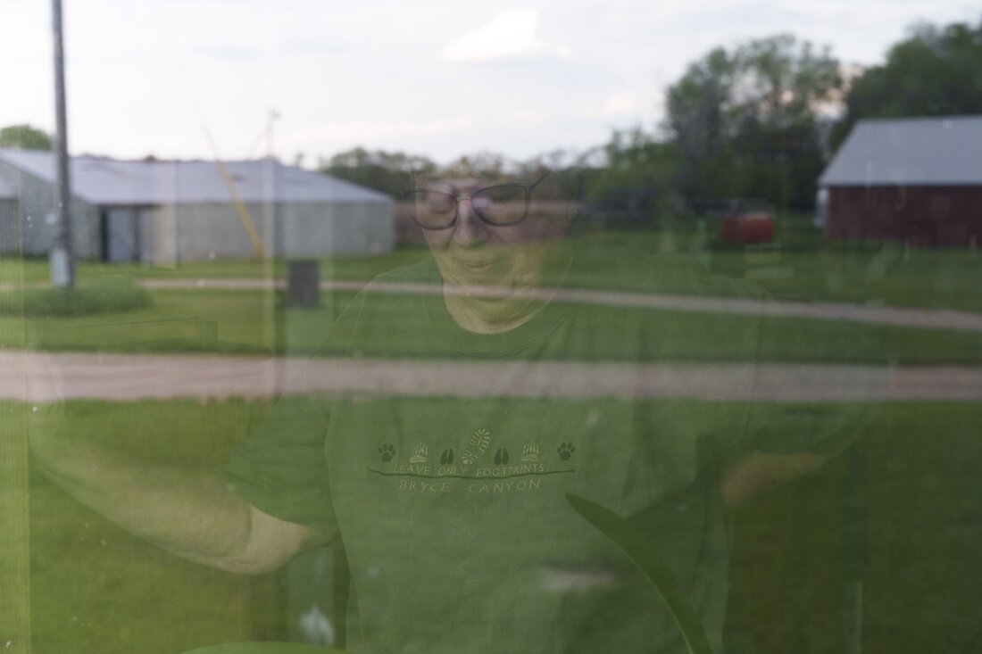 Cindie Haakenson is seen through a window of her home as the family farm is reflected before her on May 21 in Willow City, N.D. Despite a preference to remain at home, Cindie's husband, Sherwood Haakenson, needed to move to a 24-hour long-term care center.