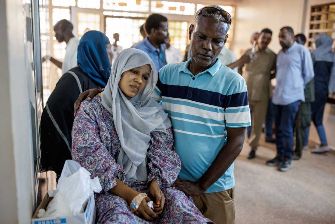 A husband comforts his wife, injured by shelling, in a hallway at the Al Nao Hospital.