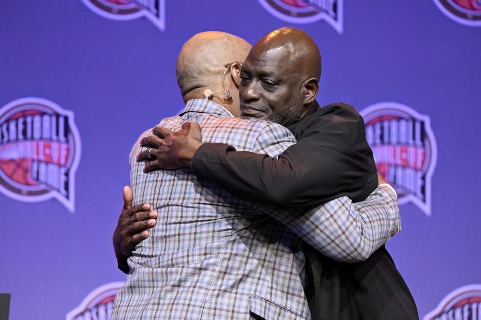 Former Lakers star Michael Cooper, right, embraces former NBA player and broadcaster Dennis Scott.