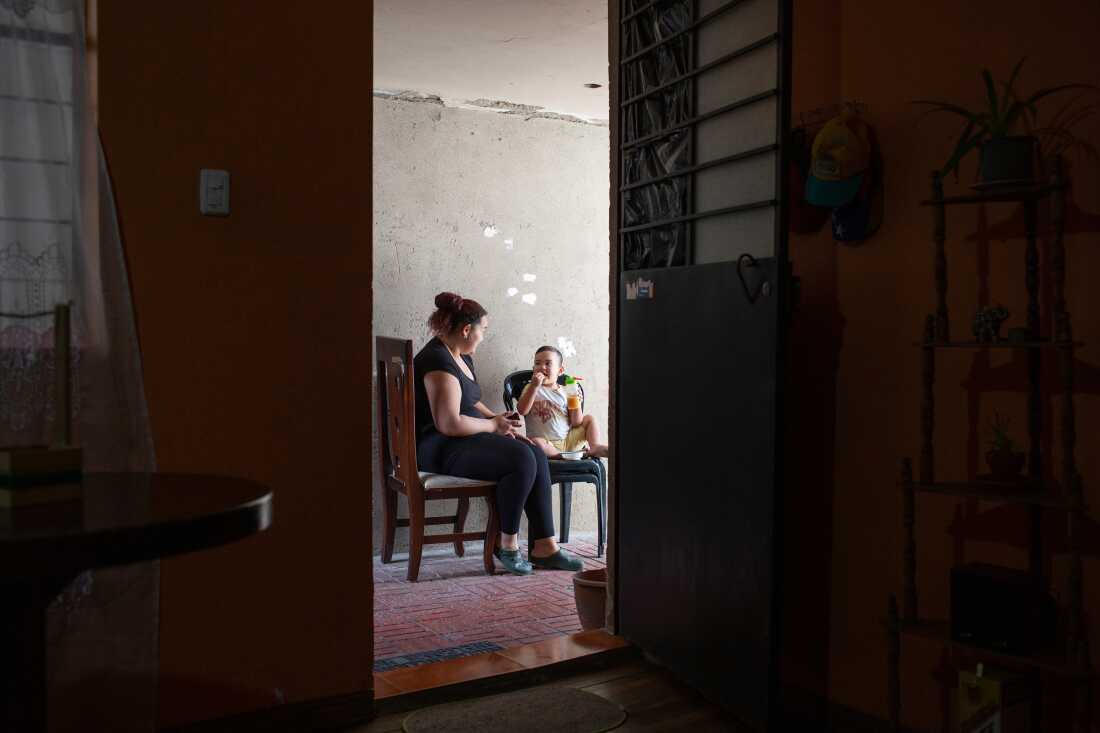 In this photo, Karen Sanabria and her son, Joshua Kaed, sit on chairs on a patio.