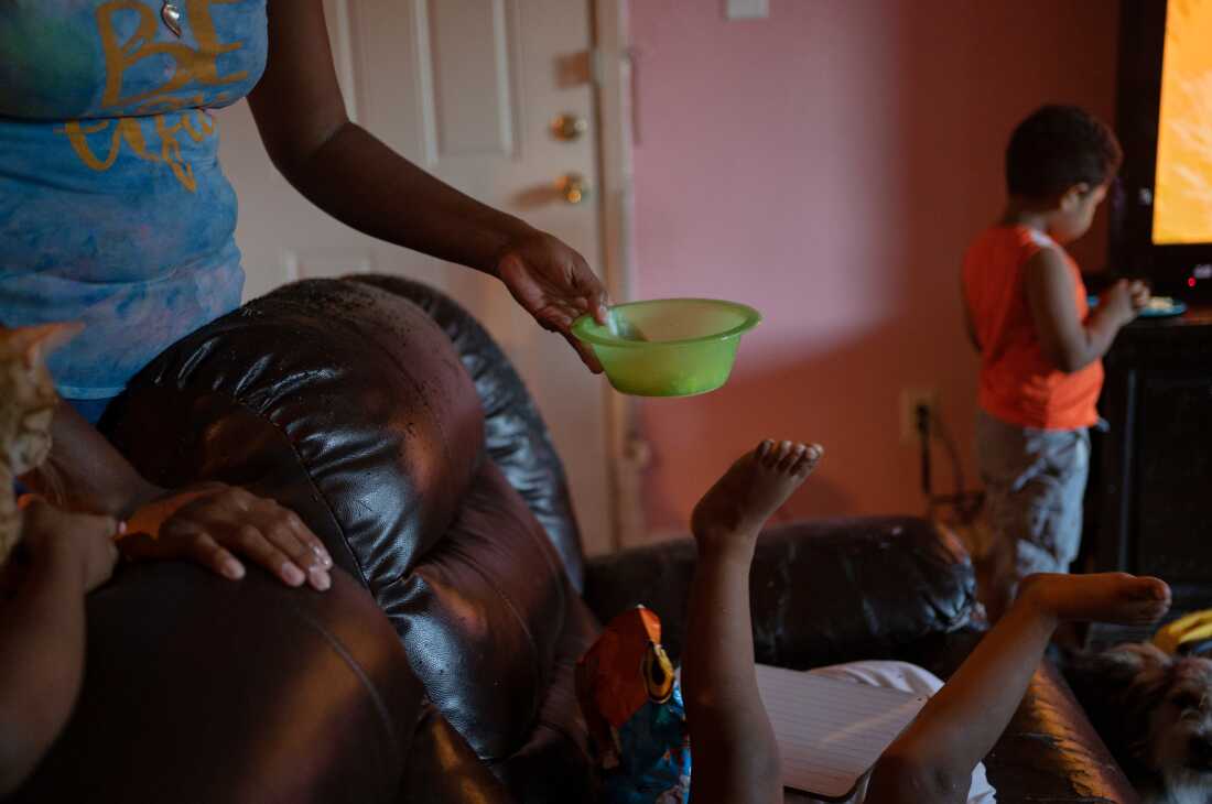 This photo shows the raised-up legs of 2-year-old Jose, who's playing on a couch. Mother Emilia Lopez's outstretch arm is holding a bowl of eggs for him.