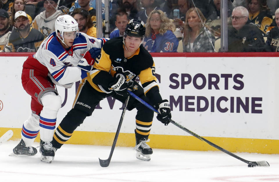 Oct 9, 2024; Pittsburgh, Pennsylvania, USA; Pittsburgh Penguins right wing Rutger McGroarty (2) moves the puck against New York Rangers defenseman Braden Schneider (4) during the first period at PPG Paints Arena. Mandatory Credit: Charles LeClaire-Imagn Images