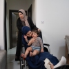 Raneem Hijazi holds her baby, Mariam, on her lap in her wheelchair, as Hijazi's mother-in-law, Soha Sakallah (standing), helps her.