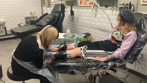 Alice getting a tattoo from Kim