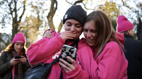 EPA Two pro-assisted dying campaigners looking at a phone and smiling