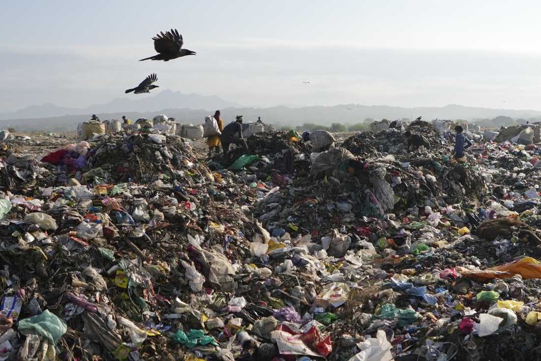 People look for reusable material at a garbage dump filled with plastic and other waste on the outskirts of Jammu, India.