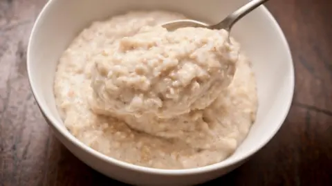 Getty Images Close-up of a bowl of porridge with a spoon on a wooden table